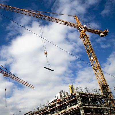 Construction site showing building with scaffolding and cranes at work